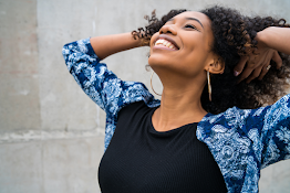 Woman standing with hand behind head smiling and looking towards the sky